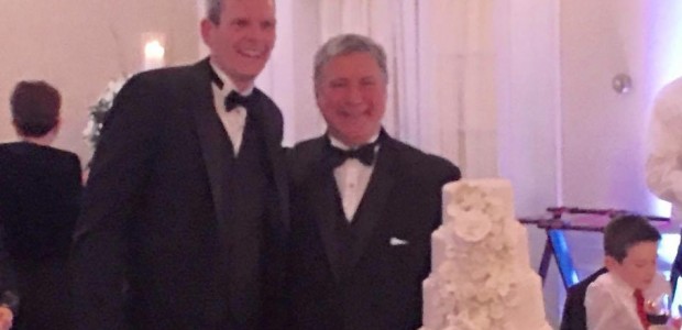 Newlyweds John Heropoulos and Richard Crook pose for a photo by their wedding cake