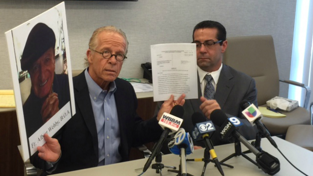 Attorney Jeff Anderson holds a picture of the accused priest and a copy of the lawsuit. (Credit: Lisa Fielding)