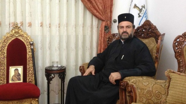 Father Gabriel Naddaf, in his living room, alongside a likeness of Mary, which, he believes, saved his life in a road accident in 2011. (Mitch Ginsburg/Times of Israel)