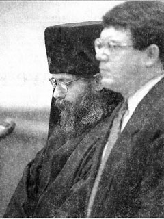 Staff photo by DON TREEGER:  Dell Scott Goodwin, left, known as Father Lazarus at a Brimfield monastery, stands with bowed head beside his lawyer, Gregory Hession, yesterday during a Palmer District Court hearing.