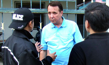 Mikhail Pletnev, founder of post-Soviet Russia's first private orchestra, is questioned by a Thai police officer in front of the muscian's Pattaya residence. Photograph: AP