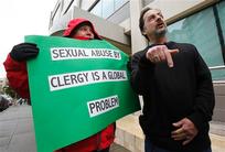 Joey Piscitelli, the Northern California Director of SNAP (the Survivors Network of those Abused by Priests) talks about Pope Benedict XVI, as Melanie Sakoda, left, holds a sign during a news conference in front of the Archdiocese headquarters.