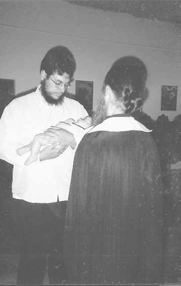 David Smith, who has horror stories to tell about his time at the monastery, holding his Godson at the latter's baptism, as Abbot Paisios watches.